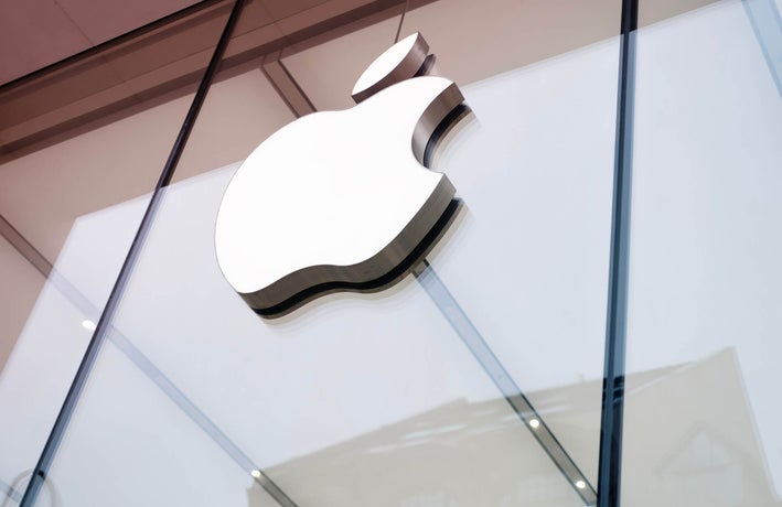 A close up shot of the outside of an Apple office with its logo displayed on front.