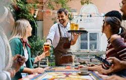 Staff member serving drinks to customers in a pub garden