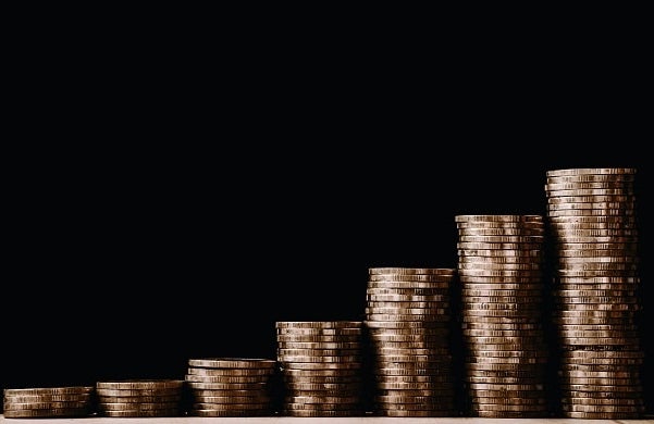 growing piles of gold coins on a table with a black background