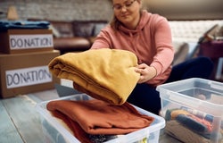 Close-up of woman sorting clothes while packing donation boxes for charity.