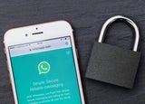 WhatsApp open on a smartphone next to a padlock