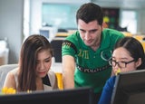 Young people gathered at a computer in a work environment